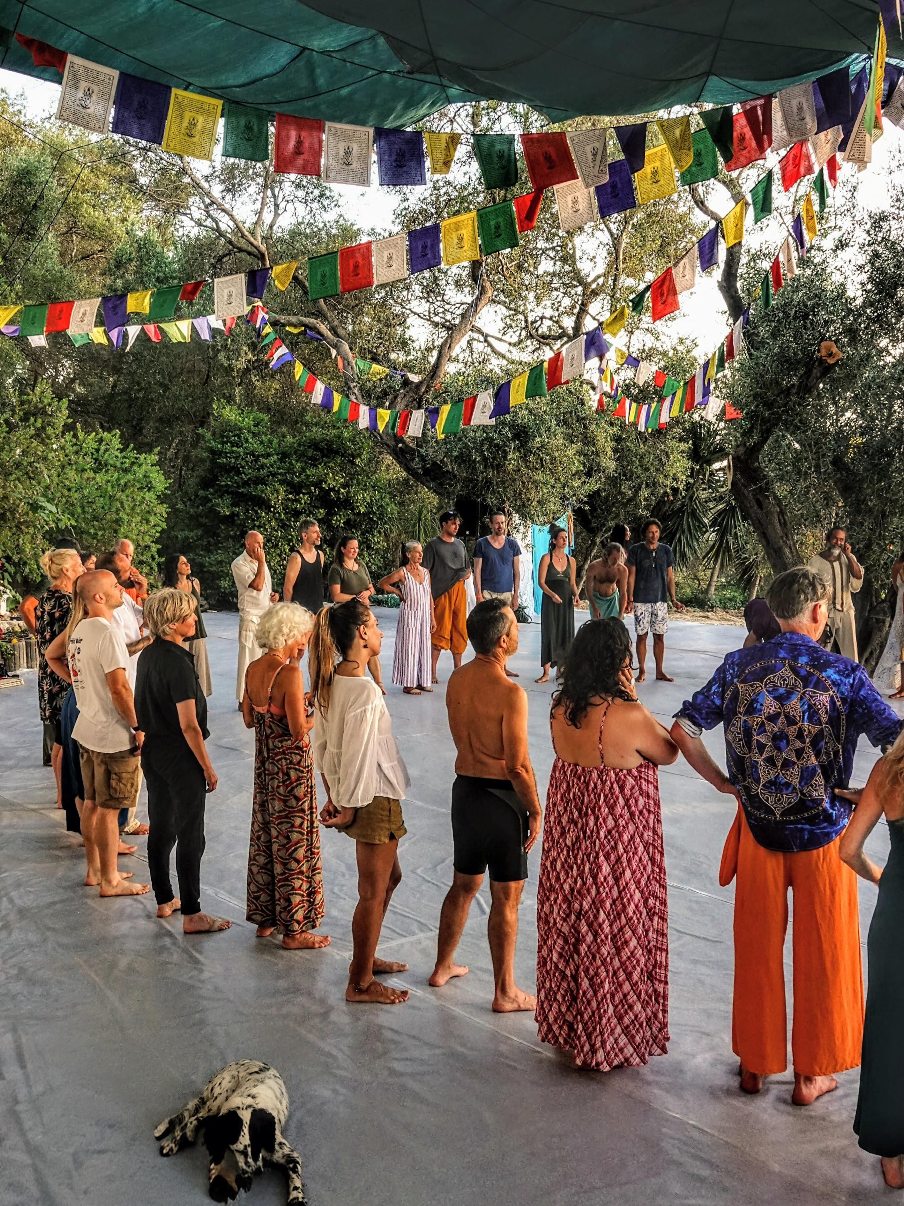 The SHINE community gathers in a circle under colourful flags on the open-air dance floor